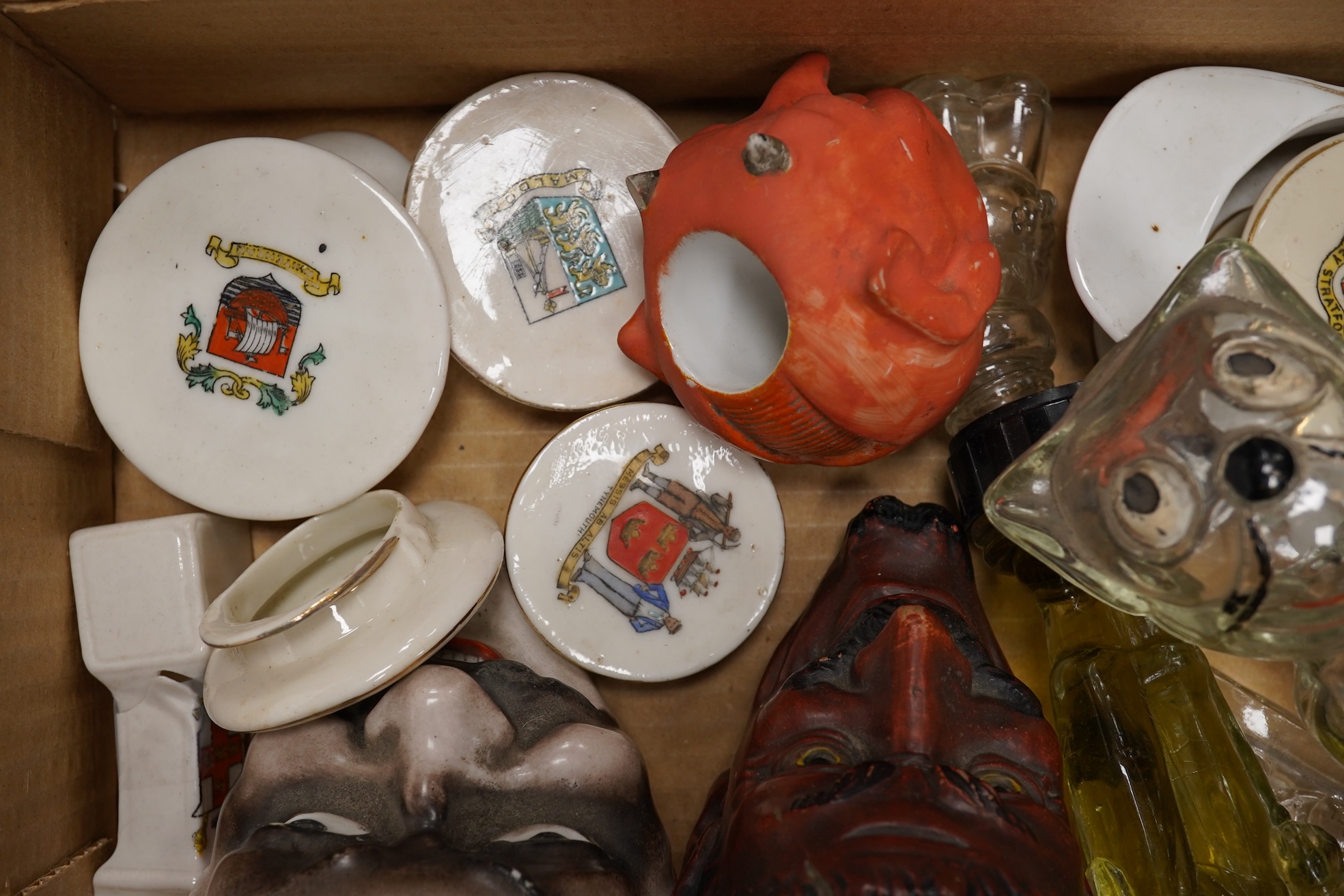 A collection of sundry items to include novelty glass bottles, devil pots and ceramic military caps